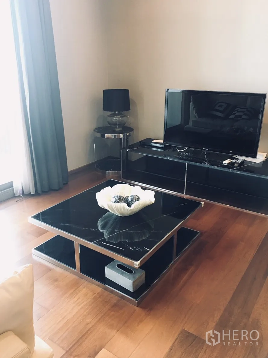 公寓 出租在Watthana, Bangkok - 客厅配黑色大理石茶几、电视柜与落地窗帘，风格简洁。