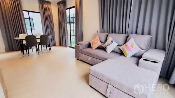 Detached House for rent in Lat Krabang, Bangkok - Spacious lounge connected to the dining corner with full-height curtains and black-framed windows.