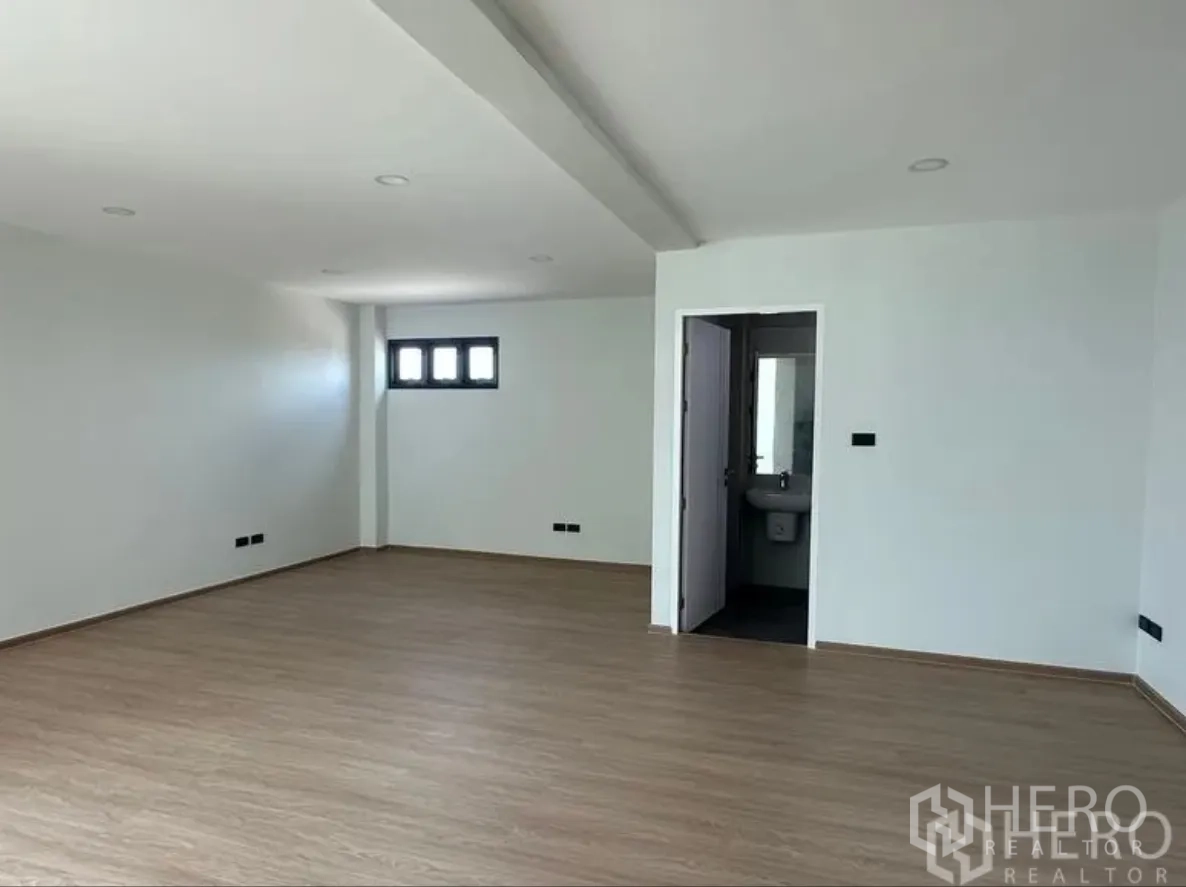 仓库 for sale in Lam Luk Ka, Pathum Thani - 宽敞办公室，木纹地面，门内可见套内卫生间。