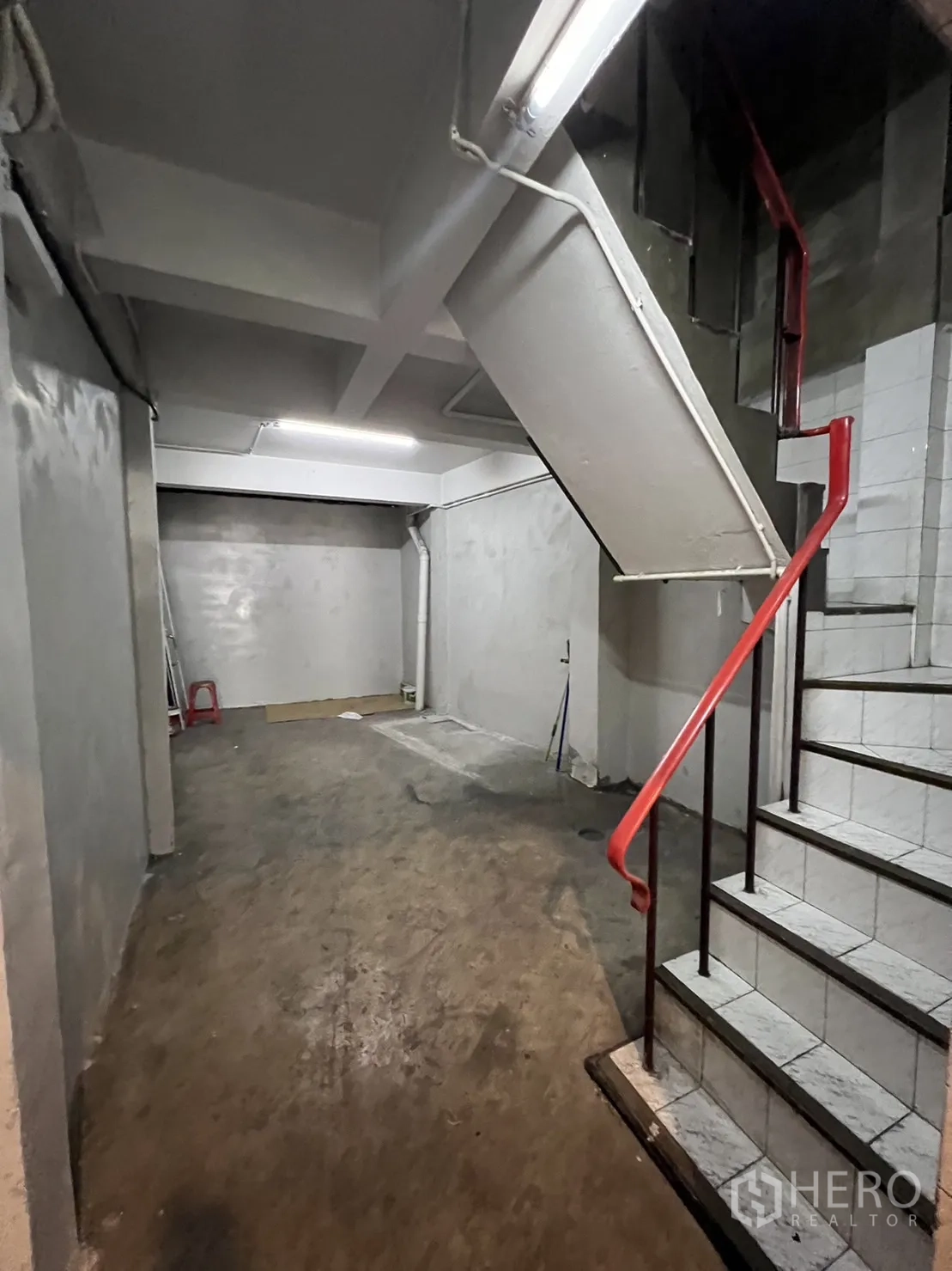 Shophouse for rent in Watthana, Bangkok - Stairwell and storage area with red handrail and worn concrete floor.
