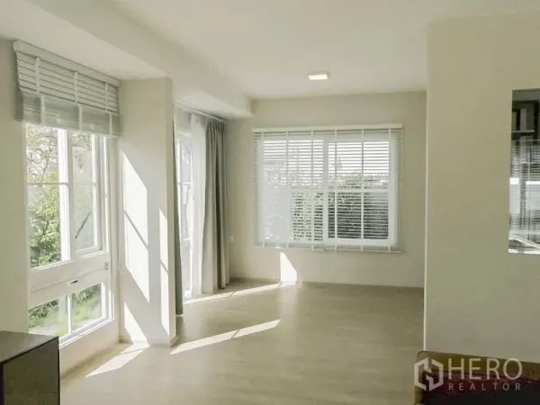 Townhouse for rent in Prawet, Bangkok - Sunlit open-plan living and dining area with multiple windows, blinds and sheer curtains overlooking greenery.