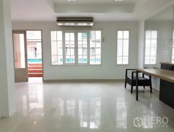 Townhouse for rent or sale in Chatuchak, Bangkok - Open plan room with glossy tile floors, wide windows, balcony door and ceiling air conditioner.