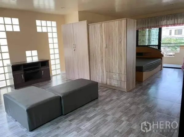 Townhouse for rent in Phra Khanong, Bangkok - Open-plan upper floor with beds, wardrobes, large windows with security grilles, and a glossy ceiling.