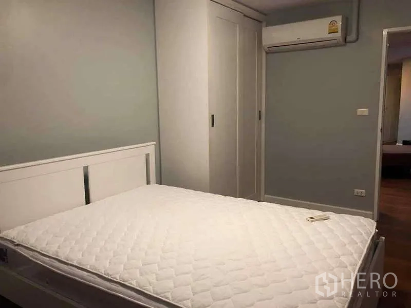 Condominium for sale in Yan Nawa, Bangkok - Bedroom corner with built-in sliding wardrobe and wall-mounted air conditioner.