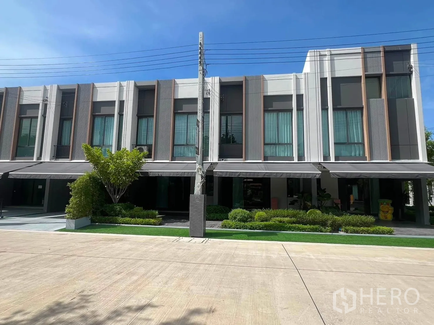 Townhouse for rent in Bang Phli, Samut Prakan - Modern two-story townhouse facade with large windows and landscaped frontage.