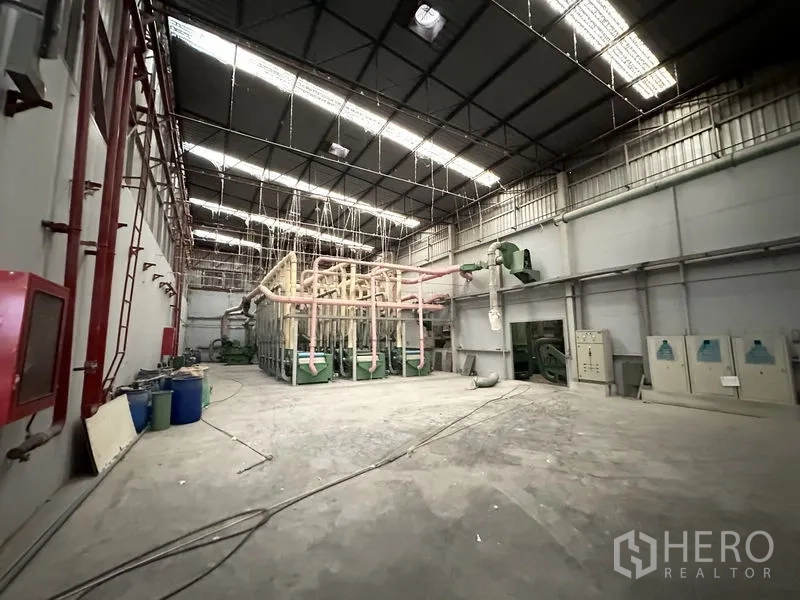 Factory for rent in Bang Bua Thong, Nonthaburi - Machinery zone with ventilation piping and control panels under skylights.