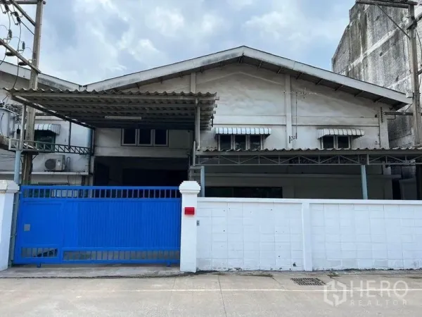 货栈 出租在Khlong Toei, Bangkok - 临街仓库外立面，蓝色滑动大门与白色围墙。