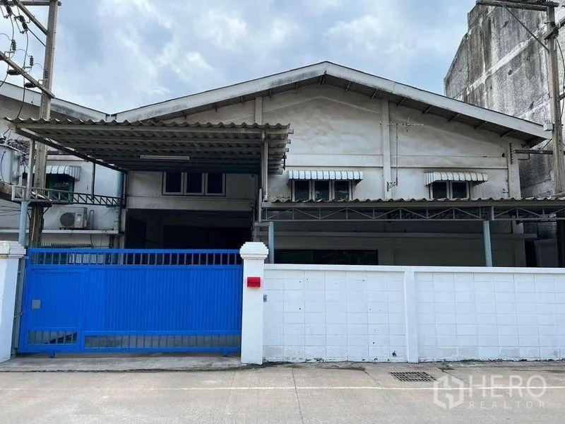 Warehouse for rent in Khlong Toei, Bangkok - Street-facing warehouse facade with blue sliding gate and white perimeter wall.