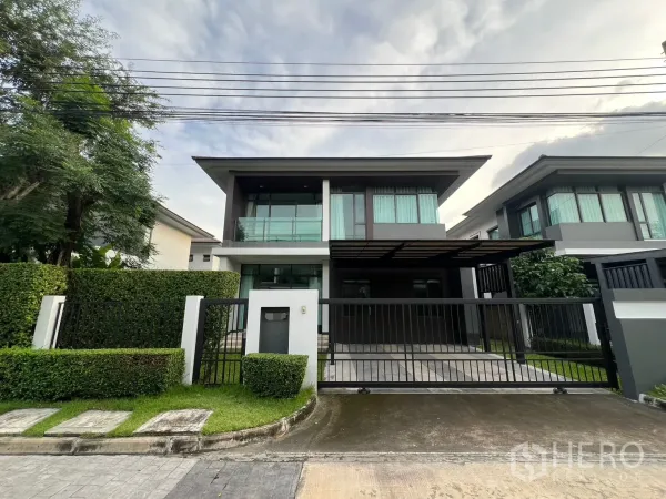 Detached House for rent in Bang Kapi, Bangkok - Front view of a modern two-storey detached house with sliding gate, driveway and upper balcony.