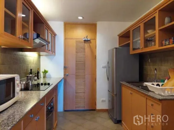 Apartment for rent - Galley kitchen with wooden cabinets, stone counters and modern appliances.