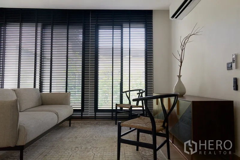 Detached House for rent in Watthana, Bangkok - Cozy sitting area with sofa, wooden chairs and tall window blinds.
