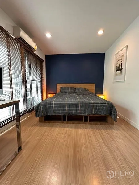 联排别墅 出售在Wang Thonglang, Bangkok - 宽敞卧室，蓝色主墙与床头灯。