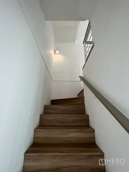 Townhouse for rent in Bang Kapi, Bangkok - Wood-tread staircase with wall light leading to the upper floors.