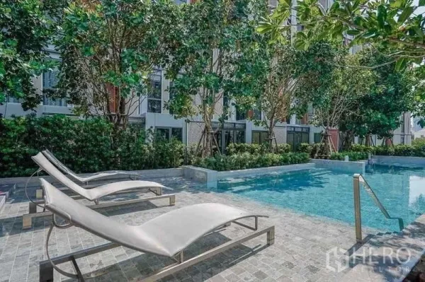 公寓 出租在Watthana, Bangkok - 公寓户外泳池，配躺椅与郁郁葱葱的树木。