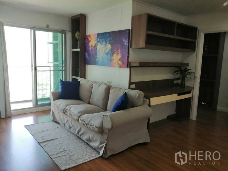 公寓 出售在Yan Nawa, Bangkok - 起居区配沙发、阳台推拉门、彩色墙画及内置书桌。