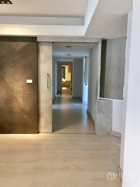 Condominium for rent in Watthana, Bangkok - Dining area under a white chandelier facing the TV wall and sofa in an open-plan space.