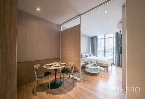公寓 出租在Khlong Toei, Bangkok - 开放式单间公寓，滑动隔断、餐桌与落地窗采光充足。