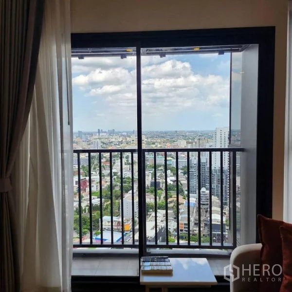 公寓 出租在Watthana, Bangkok - 客厅推拉玻璃门通向阳台，高楼层全景城市景观。