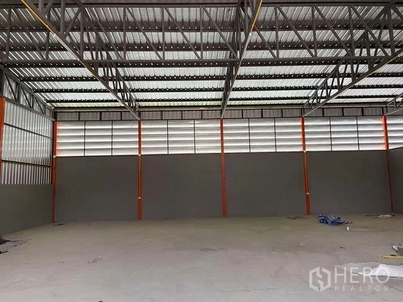 Warehouse for rent in Lam Luk Ka, Pathum Thani - Spacious open-plan warehouse interior with steel truss roof, louvered vents, and concrete floor.