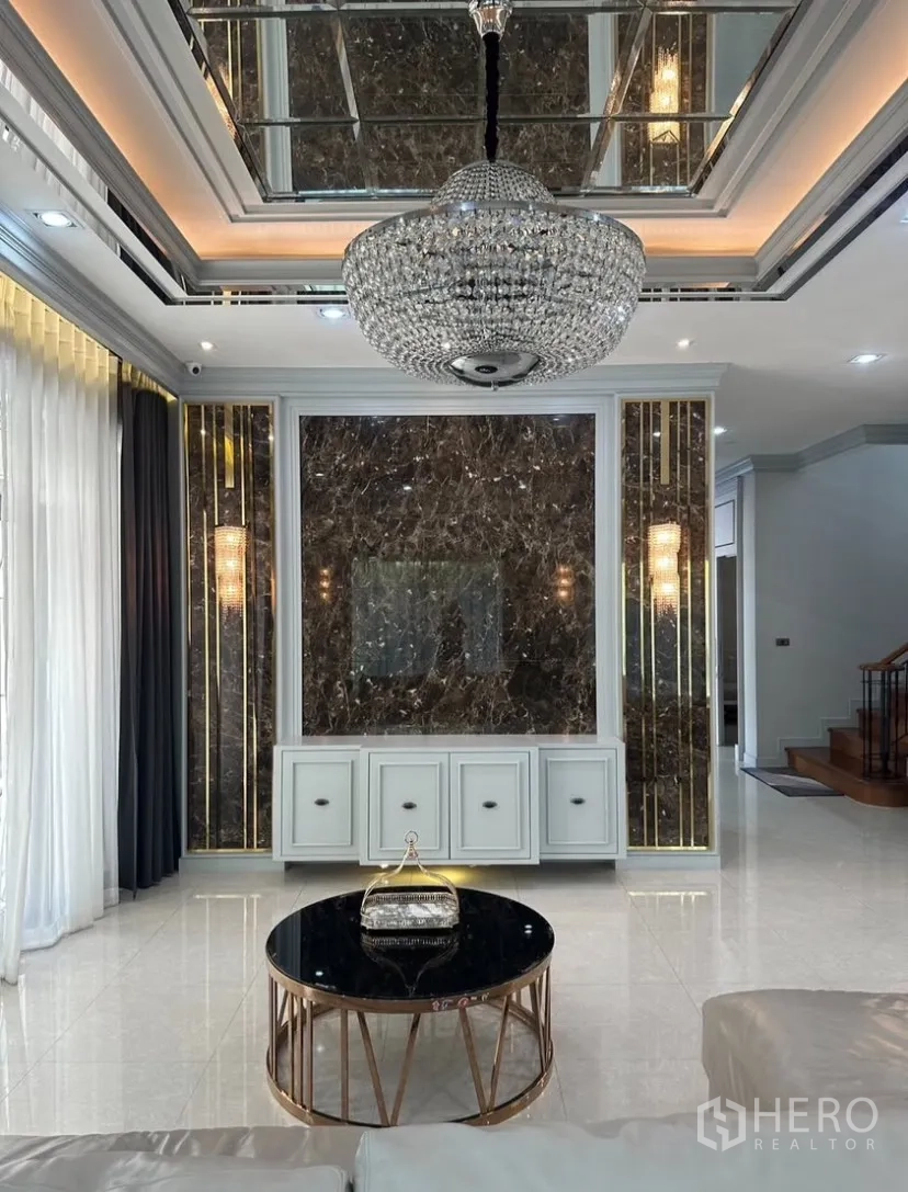 Detached House for rent or sale in Prawet, Bangkok - Living area facing the staircase and pantry cabinetry, showing tray ceilings and downlights.