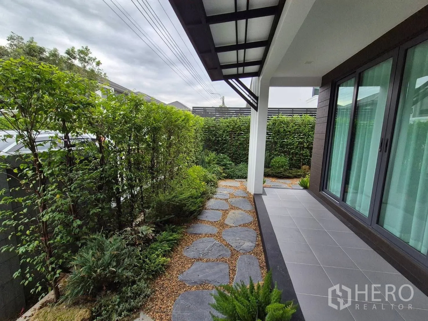 Detached House for sale in Bang Kruai, Nonthaburi - Landscaped side garden with stepping‑stone path, hedges and covered terrace.