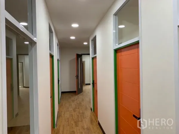 办公空间 出租在Khlong Toei, Bangkok - 采光良好的走廊，多间独立办公室，橙色门与高侧窗。