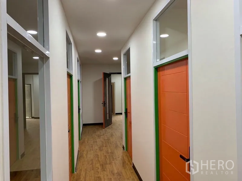 办公空间 出租在Khlong Toei, Bangkok - 采光良好的走廊，多间独立办公室，橙色门与高侧窗。