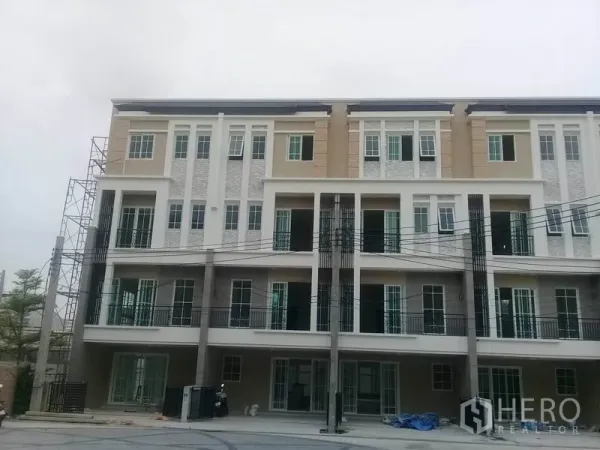 Home Office for rent in Bang Na, Bangkok - Four-storey modern home office facade with balconies and tall windows in a gated Bang Na project.