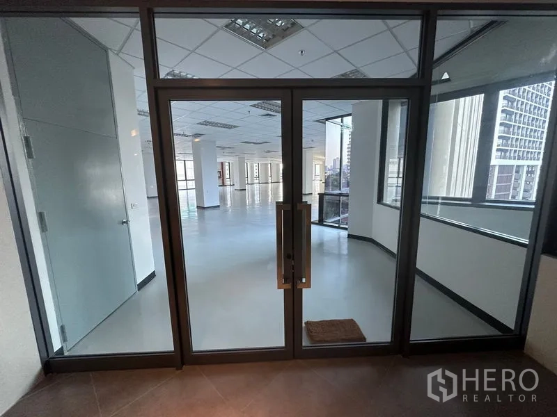 办公空间 出租 - 玻璃双开门入口，通向明亮的开放式办公区与城市景观窗。