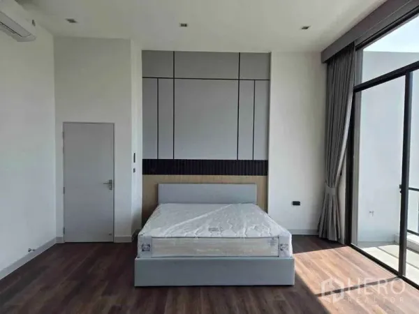 Detached House for rent in Bang Phli, Samut Prakan - Spacious bedroom with feature wall, double bed and floor-to-ceiling sliding doors to a balcony.