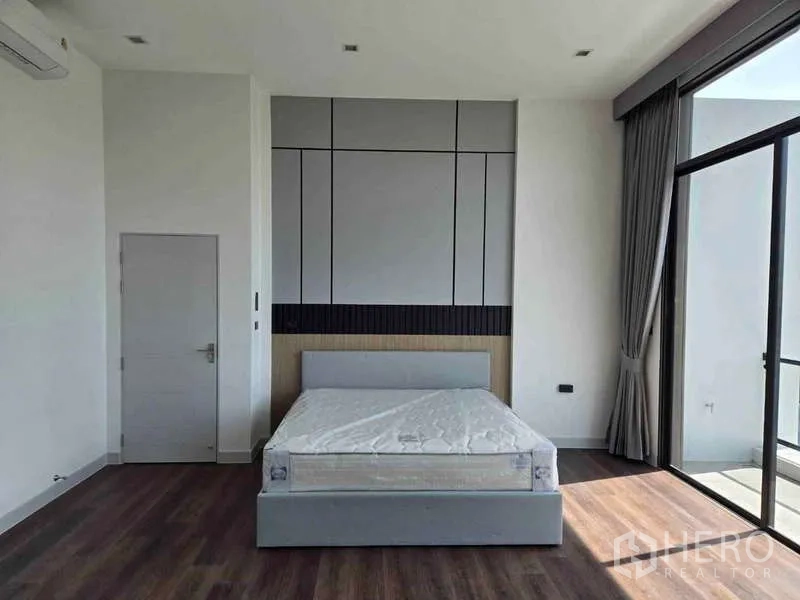Detached House for rent in Bang Phli, Samut Prakan - Spacious bedroom with feature wall, double bed and floor-to-ceiling sliding doors to a balcony.
