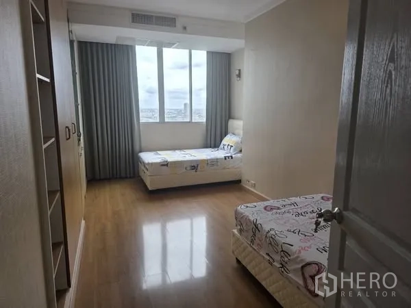Condominium for rent in Khlong Toei, Bangkok - Second bedroom with two single beds and a large window.