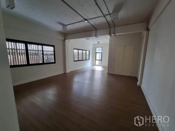 Home Office for rent or sale in Phaya Thai, Bangkok - Long open office area with multiple windows, white walls and wood-look flooring.