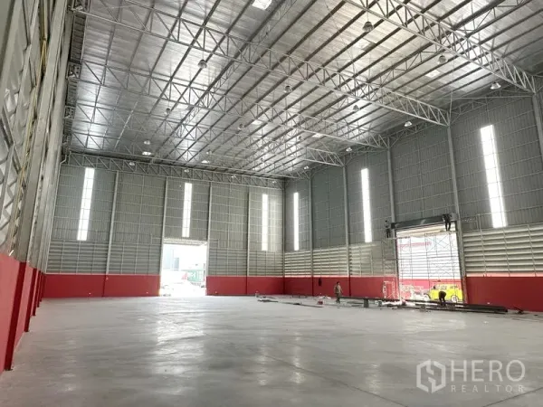 货栈 出租在Khlong Luang, Pathum Thani - 仓库内部高挑钢梁屋顶，抛光混凝土地面，采光带与大型卷帘门。