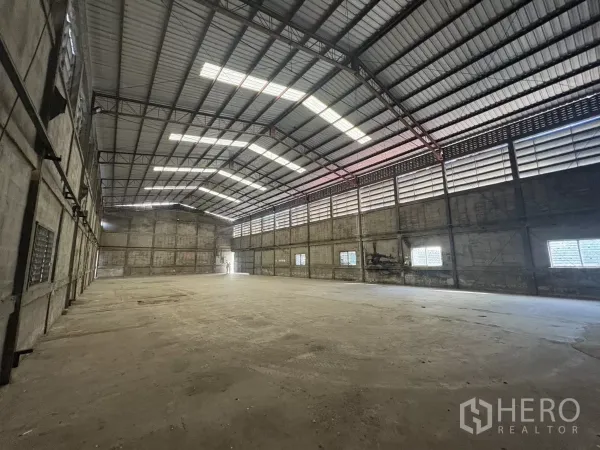 Warehouse for rent in Khlong Toei, Bangkok - Spacious column‑free warehouse interior featuring high steel truss roof and skylight panels.
