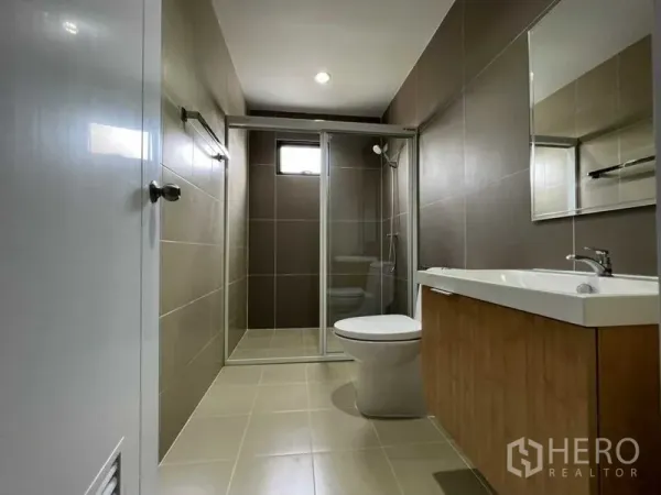 联排别墅 出租在Wang Thonglang, Bangkok - 现代浴室，玻璃干湿分离淋浴间、镜柜与木纹洗手台。