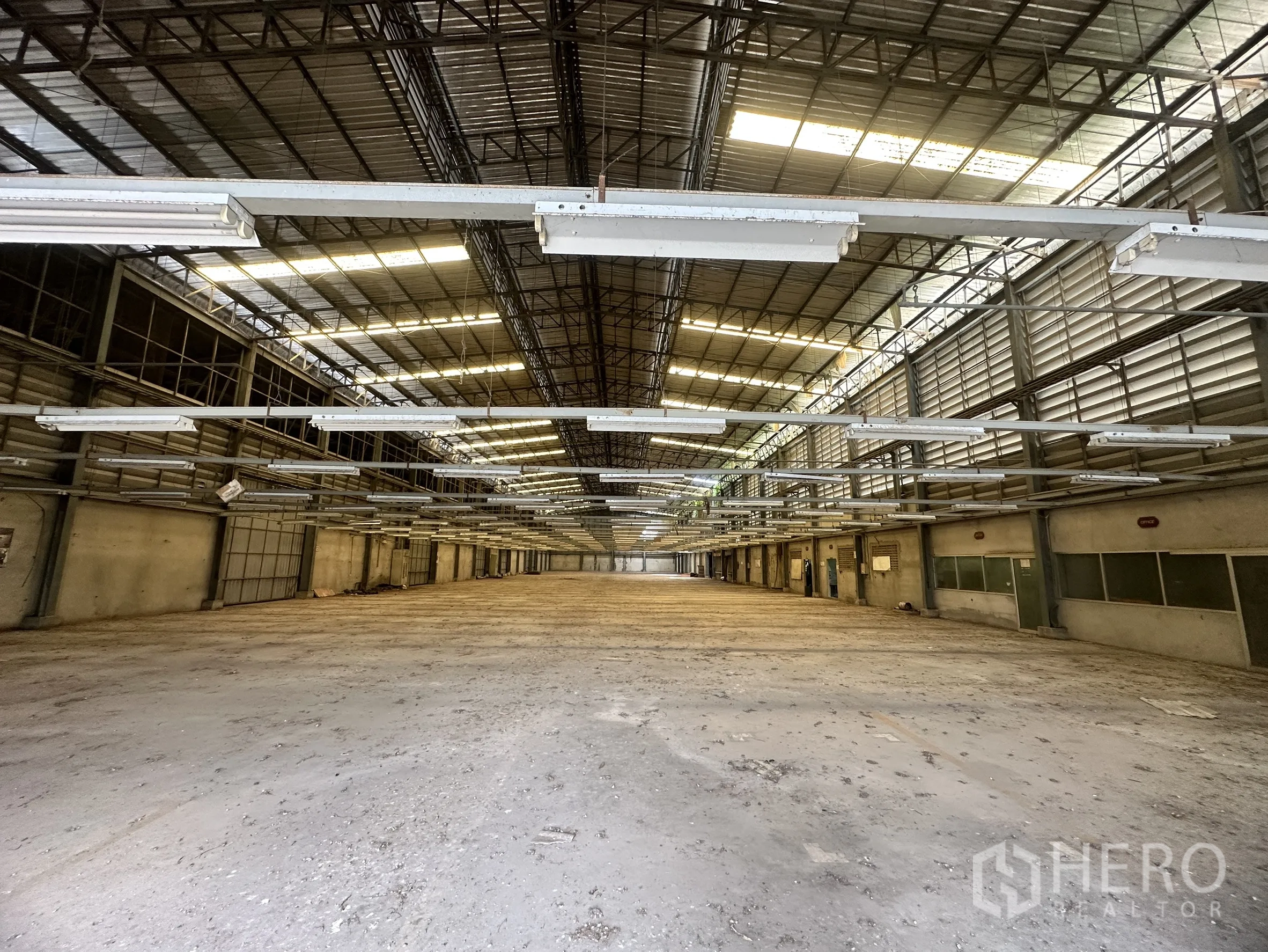 Factory for sale in Sai Noi, Nonthaburi - Wide manufacturing space with ventilation louvers and even concrete flooring.