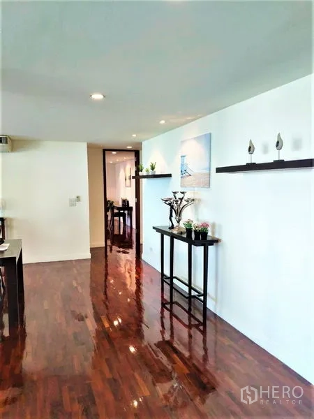 Condominium for rent in Bang Rak, Bangkok - Bright hallway with polished hardwood floors, floating wall shelves and a console table leading toward the dining area.