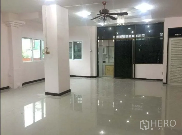 Detached House for rent in Chatuchak, Bangkok - Large living area with columns, ceiling fan and sliding glass to the kitchen zone.