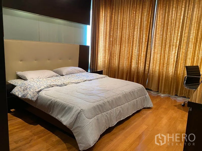 公寓 出租在Khlong Toei, Bangkok - 主卧配特大床、木地板、金色落地窗帘和书桌。
