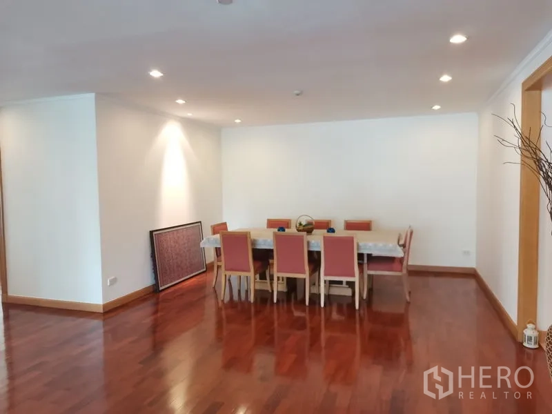 Condominium for rent in Khlong Toei, Bangkok - Spacious dining area with an eight-seat table, recessed lighting, and polished wooden flooring.