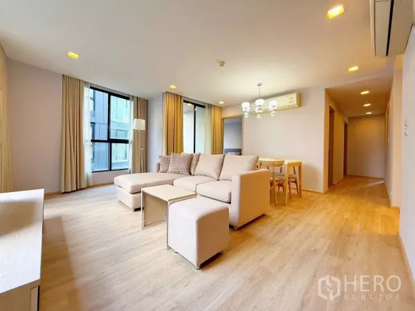 公寓 出租或出售在Watthana, Bangkok - 开放式客餐厅，L形沙发与吊灯，走廊通往卧室。
