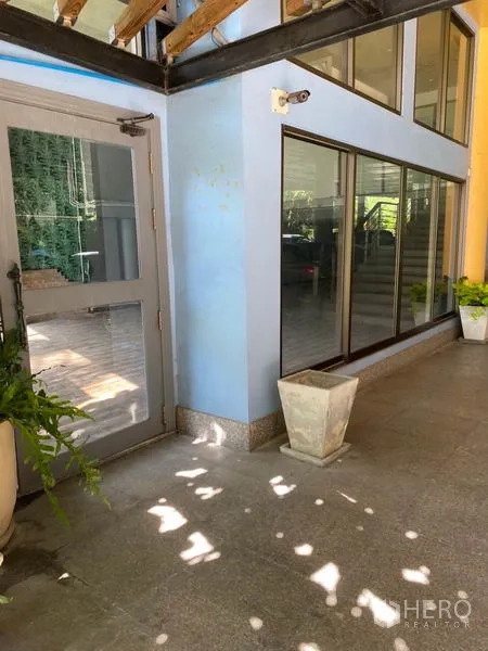 零售空间 出租在Watthana, Bangkok - 玻璃门面与侧门，带顶走道与盆栽。