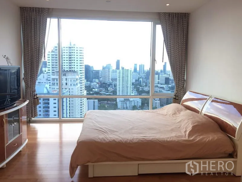 公寓 出租或出售在Watthana, Bangkok - 主卧配木地板与超大全景窗，城市景观一览无余。