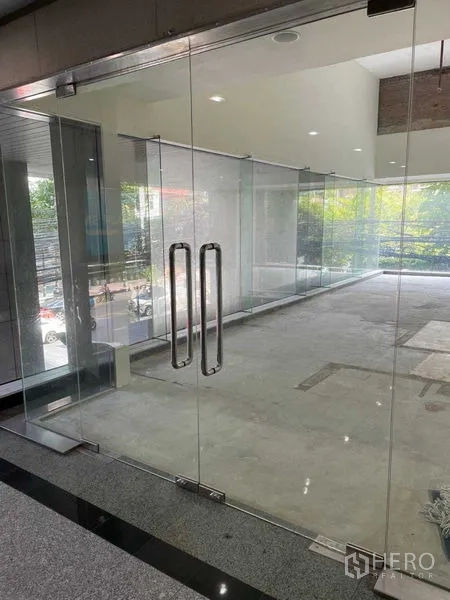 办公空间 出租在Watthana, Bangkok - 玻璃双开门入口，未装修的办公区可见街景。