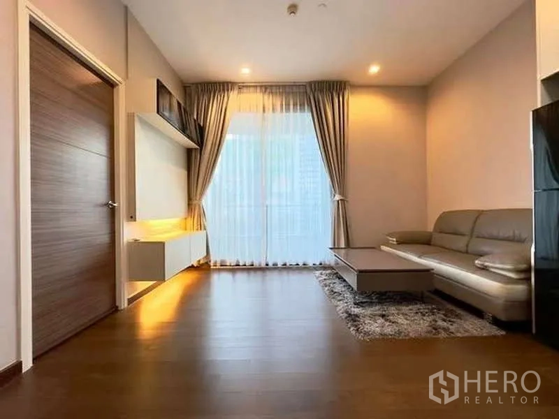 คอนโด ขายในRatchathewi, Bangkok - พื้นที่นั่งเล่นพร้อมโซฟา โต๊ะกลาง และประตูกระจกบานเลื่อนพร้อมผ้าม่าน