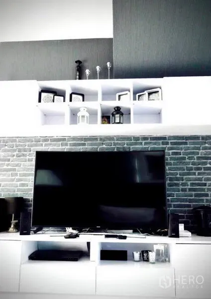 Detached House for rent or sale in Bang Phli, Samut Prakan - Media wall with large flat-screen TV, white shelving and gray brick accent