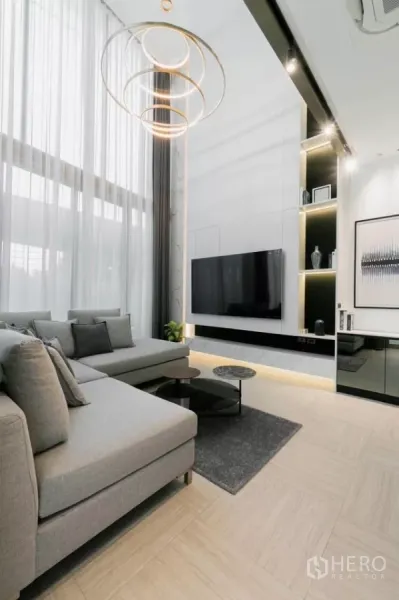 Townhouse for sale in Chatuchak, Bangkok - Modern living area with tall windows, ring chandelier and feature wall TV.