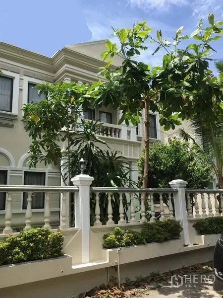 独立式住宅 出租在Khlong Toei, Bangkok - 两层新古典立面的独栋别墅，带阳台、白色栏杆与热带树木。