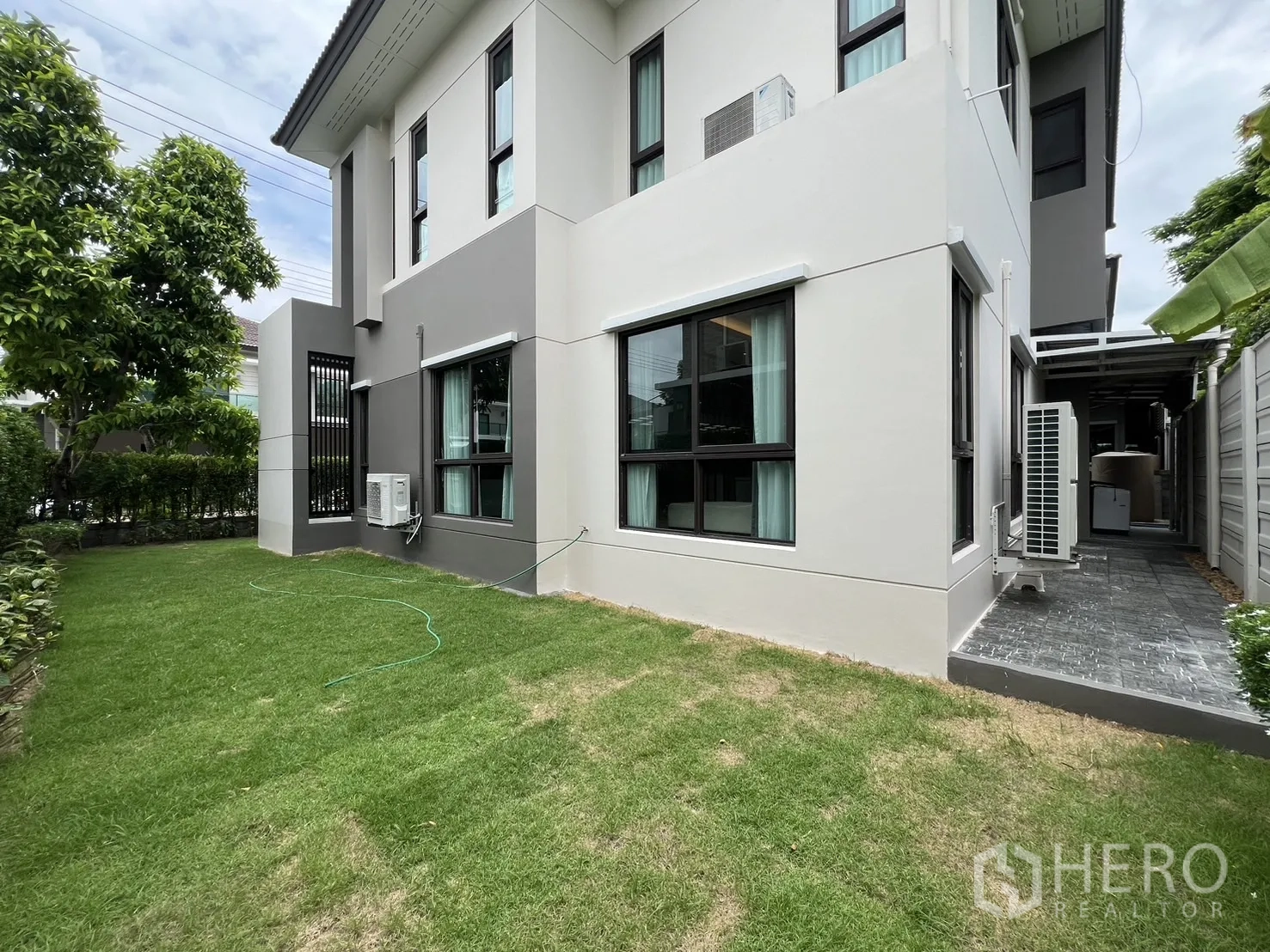 Detached House for rent or sale in Prawet, Bangkok - Side lawn wrapping around the house with greenery and hedges.